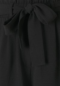 Shorts en tissu noir avec une large ceinture élastique et un détail de ceinture nouée à l'avant. Texture lisse avec un design minimaliste.