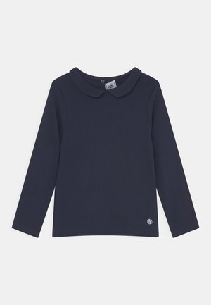 Granatowa koszula z długim rękawem, zaokrąglonym kołnierzem i małym logo żaglówki blisko dołu, rozłożona na białym tle.