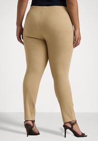 Beige stretch leggings, joissa on sileä tekstuuri ja tiukka muotoilu, keskitason vyötärö ja kapea leikkaus, yhdistetty ruskeisiin korkokengiin.