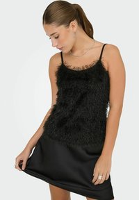 Robe noire avec un corsage texturé et duveteux doté de fines bretelles, une jupe en satin lisse, et un ourlet simple.