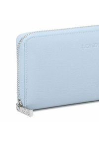 Billetera de cuero azul claro con una textura suave, cremallera plateada y detalle de logo en relieve. Forma rectangular con esquinas redondeadas.