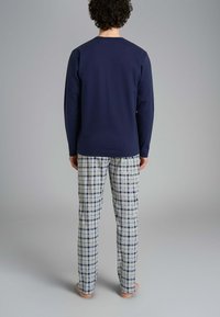 Maglia a maniche lunghe blu navy e pantaloni del pigiama a quadri con accenti blu, bianchi e verdi. Tessuto morbido e comodo con vestibilità rilassata.