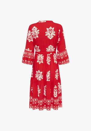 Punainen kuvioitu mekko, jossa on valkoisia kukkamotiiveja, liehuvat hihat ja kerroksellinen helma. Valmistettu kevyestä kankaasta, jossa on rento istuvuus.