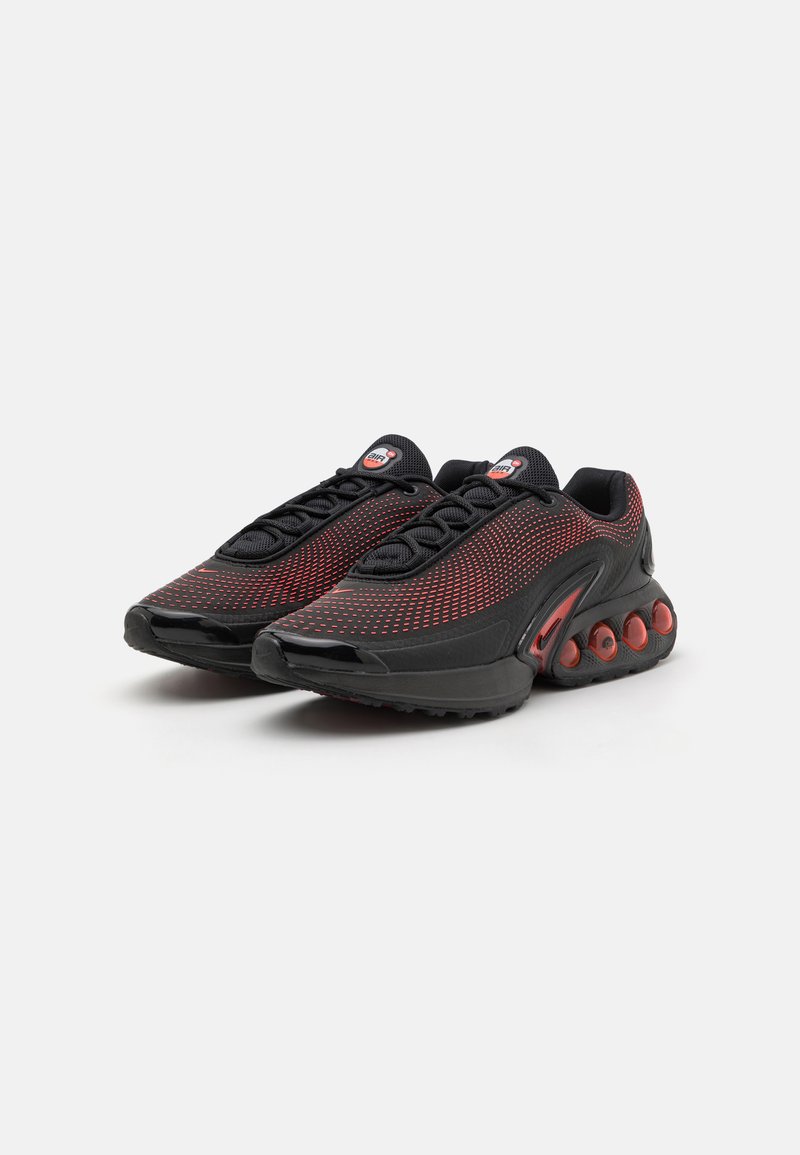 Des chaussures de sport noires et rouges avec un dessus en maille, dotées d'un rembourrage circulaire sur la semelle et d'accents réfléchissants sur les côtés.
