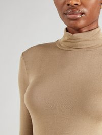 Beige Rollkragensweater aus geripptem Material, mit enganliegendem Schnitt, langen Ärmeln und hohem, schmalem Kragen. Glatte Textur.