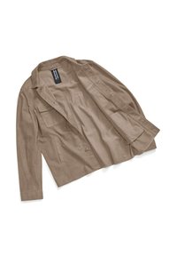 Giacca beige leggera con colletto aperto, chiusura a bottoni e tasca sul petto. Texture liscia con maniche lunghe e design su misura.