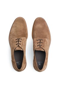 Scarpe oxford in suede marrone con punta tondeggiante, lacci, cuciture tonali sottili e una fodera interna liscia, posizionate su uno sfondo bianco.