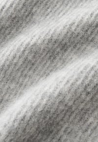 Weiches, hellgraues Wollgewebe mit einer flauschigen Textur und sichtbarem gestricktem Rippmuster im Nahaufnahme, das sanfte Falten zeigt.