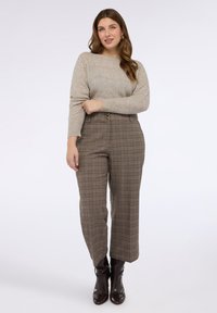 Sweter w jasnym beżu z teksturowanymi paskami; brązowe spodnie w kratę z wysokim stanem i dwoma guzikami; błyszczące brązowe botki.