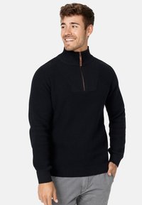 Pull-over en maille noir avec un col montant, doté d'une fermeture éclair quart et d'un motif texturé. Les poignets et l'ourlet côtelés assurent un ajustement serré.