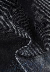 Denimstof met een donkerblauwe kleur en een subtiele textuur; heeft fijne witte stiksels langs de randen, wat een zichtbaar patroon creëert.