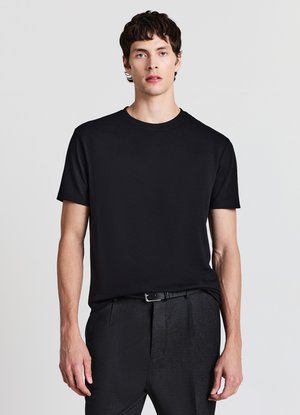 T-shirt noir à manches courtes en tissu lisse avec un col rond, associé à un pantalon gris au fini texturé et à une ceinture.