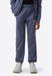 Plave trenirke od glatkog materijala s elastičnim pojasom, s tiskanim logotipom na lijevom bedru i suženim manšetama na gležnjevima.