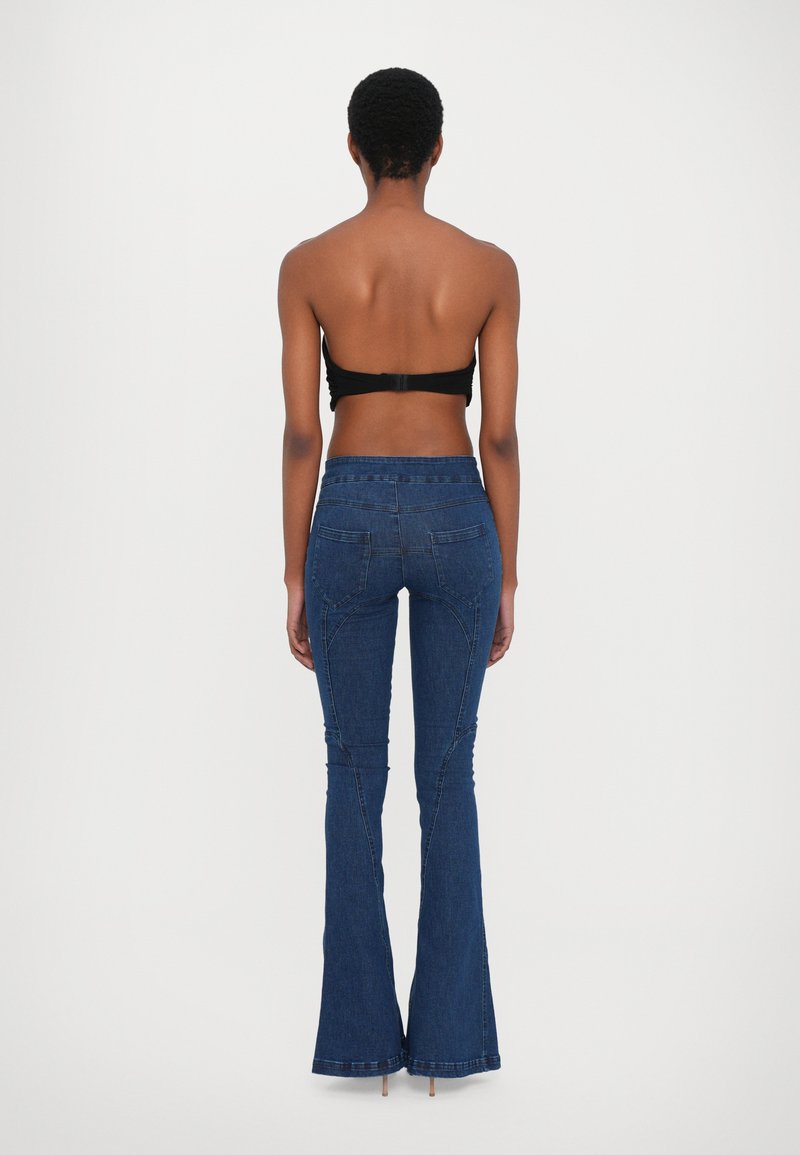 Mörkblå utsvängda denimjeans med en åtsittande midja, som har bakfickor och kontrasterande sömmar. Slät textur och subtil lyster.