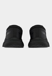 Μαύρα αθλητικά παπούτσια με επενδεδυμένο κολάρο και υφασμένα πέλματα, με ομαλή επιφάνεια και αντανακλαστικές λεπτομέρειες στις πλευρές.