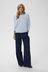 Modro svetel pleten pulover s širokim izrezom in tremi četrtinastimi rokavi, kombiniran s temno modrimi širokimi hlačami. Gladek tekstura, sproščen kroj.