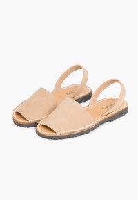 Bežinės zomšinės slingback sandaļos su atvira pirštų dalimi, plokščiu guminiais padu ir baltu siuvimu palei kraštą. Paprastas, minimalistinis dizainas.