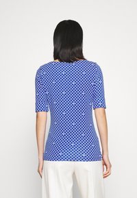Modrá vzorovaná halenka s krátkými rukávy, texturovaná tkanina, s geometrickým designem. Přiléhavý střih a široký výstřih.