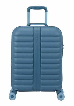 Maleta rígida azul con asa telescópica y cuatro ruedas giratorias, con estrías horizontales y cremallera central.