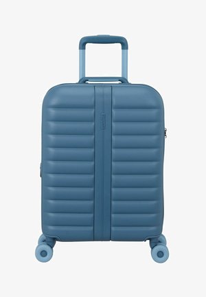 Maleta rígida azul con asa telescópica y cuatro ruedas giratorias, con estrías horizontales y cremallera central.