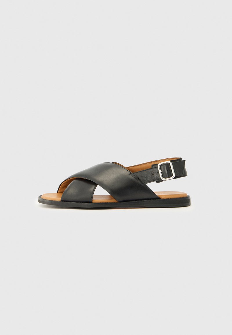 Sandalo in pelle nera con cinghie incrociate, punta aperta e cinturino alla caviglia con fibbia in metallo. Intersuola marrone e suola nera. Design semplice.