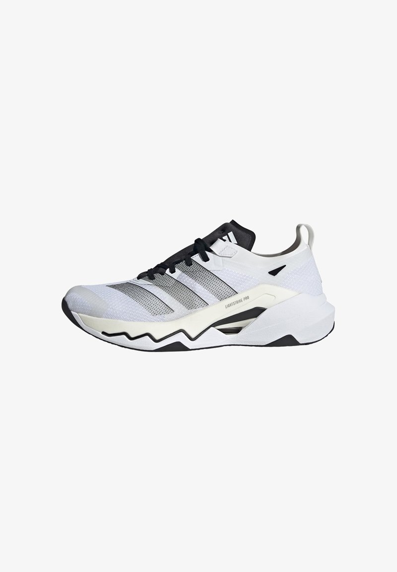 Scarpa da atletica bianca e nera con tomaia in rete, motivo testurizzato e suola spessa a zig-zag per trazione e supporto.