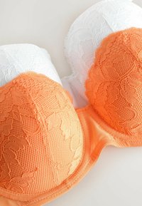 Lace push-up bh met witte en oranje cups; ingewikkeld bloemmotief op de cups, gladde textuur en zachte onderband.