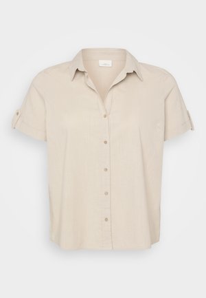 Bež srajca s kratkimi rokavi in pointed ovratnikom, z gumbnim zapiranjem spredaj in zavihanimi rokavi. Narejena iz lahkega, teksturiranega blaga.