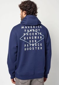 Felpa blu navy con cappuccio regolabile; presenta testo bianco e design geometrico sul retro. Il materiale sembra morbido e strutturato.