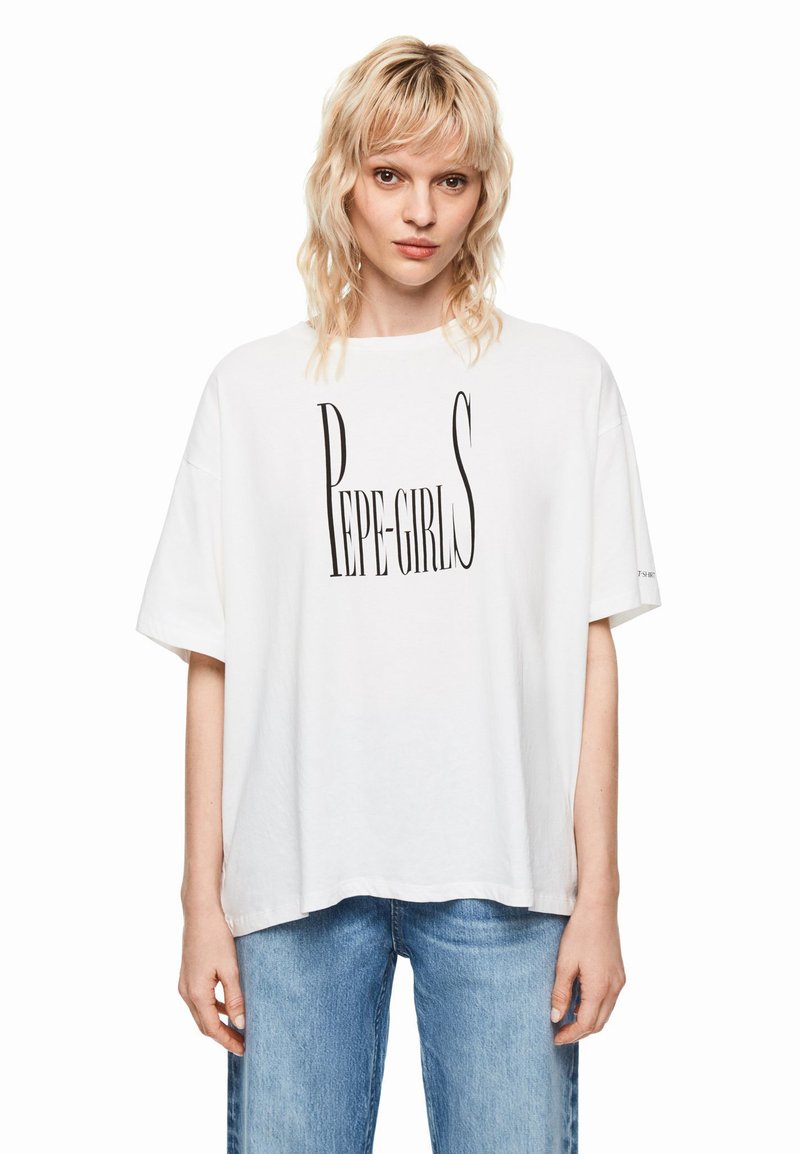 T-shirt bianca oversize con scritta nera "PEPE-GIRLS", in cotone, maniche corte, collo rotondo, vestibilità casual. Tessuto leggero visibile.