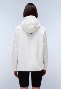 Weißer Kapuzenjacke mit lockerem Schnitt, ausgestattet mit einer zentralen Rückennaht und verstellbarer Kapuze, kombiniert mit schwarzen Shorts. Glatte Textur.