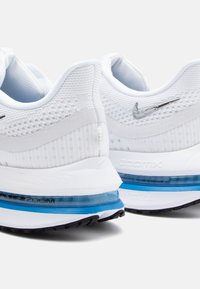 Pantofi sport albi cu partea superioară din plasă, accente argintii și detalii de amortizare în nuanța albastră. Superfață texturată și design cu toc rotund.