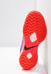 Nike-skoled med en livlig röd färg, zick-zack mönster och kontrasterande svarta logotypdetaljer på en vit botten.