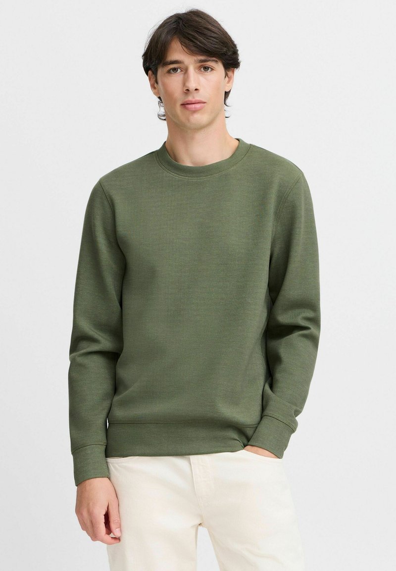 Sudadera verde oliva hecha de una tela suave, con cuello redondo y mangas largas, con puños y dobladillo de canalé. Diseño simple y texturizado.