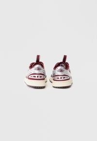 Ασημί και μπορντώ sneakers με υφή στην επάνω πλευρά, διχτυωτά πάνελ, χοντρή κρέμα μεσαία σόλα και σκούρα καουτσούκ εξωτερική σόλα, με λογότυπο στην φτέρνα.