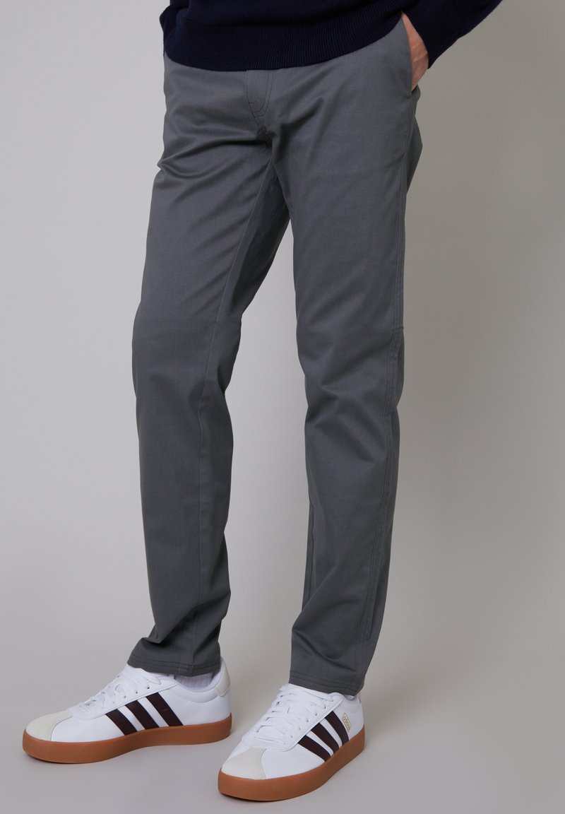 Gray cotton chinos with a straight-cut design, featuring two side pockets and a smooth texture. Paired with white sneakers and brown accents.