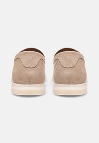 Beige suède instappers met een ronde neus, gestikte accenten en een lichte zool. Voorzien van een subtiel logo op de achterkant.