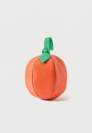 Pochette ronde en cuir orange en forme de pêche avec une poignée en boucle en cuir vert et un détail de feuille sur le dessus.