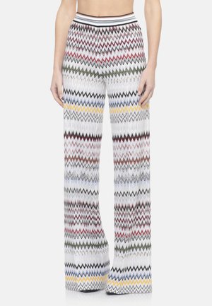 Pantaloni donna a gamba larga a vita alta con motivo a zigzag multicolore su sfondo bianco, indossati da vita a piedi.