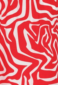 Rode en witte stof met een golvend, abstract patroon. De textuur is glad, met gedurfde contrastkleuren die dynamische visuele belangstelling creëren.