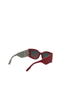 Czerwone prostokątne okulary przeciwsłoneczne z gradientowymi soczewkami. Zauszniki mają czarno-biały paskowany wzór. Wykonane z matowego plastiku, o eleganckim designie.