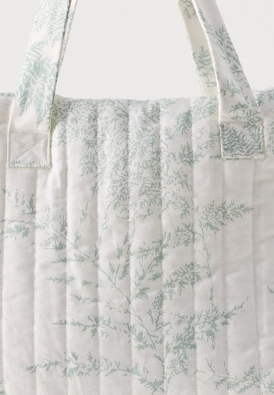 Valge tikitud kott, millel on vertikaalsed õmblused ning õrnad helerohelised lehemustrid riidest sangadel ja kotti kehal.