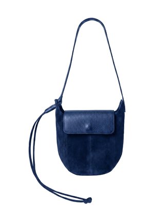 Sac bandoulière bleu marine en cuir et suède avec fermeture à rabat et longue sangle réglable avec détail pompon sur fond blanc.