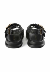 Sandalias negras con correas de tela texturizada, detalles en dorado y una suela negra lisa. Diseño de espalda abierta para facilitar su uso.