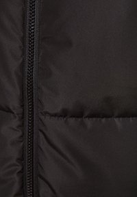 Black padded jacket fabric, featuring a smooth texture and a sturdy zipper with a honeycomb design along one side.