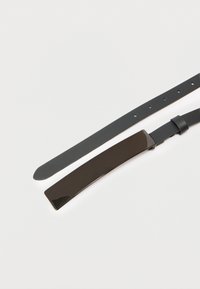 Μαύρη δερμάτινη ζώνη με λαμπερή, ορθογώνια μαύρη μεταλλική αγκράφα. Το λουρί διαθέτει ομοιόμορφα τοποθετημένες τρύπες για ρύθμιση.