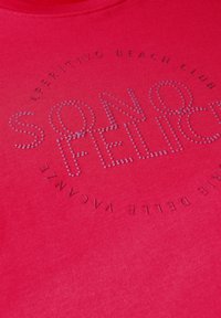 T-shirt en coton rouge avec un col rond, décoré de strass argentés formant les mots "SONO FELICE" et "APERITIVO BEACH CLUB" autour.