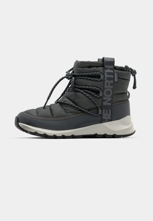 Stivale alla caviglia imbottito in grigio scuro con finitura testurizzata, dotato di chiusura con lacci e logo "THE NORTH FACE" sul lato. Suola in gomma con trazione.
