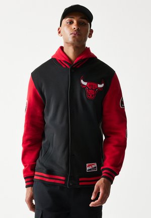 Veste universitaire noire et rouge avec capuche, présentant un logo de taureau brodé sur la poitrine et un bord-côte rayé aux poignets et à l'ourlet.