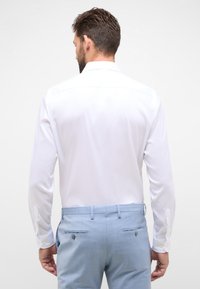 Witte blouse met lange mouwen van een soepele stof, voorzien van een klassieke kraag en knopenmanchetten, gecombineerd met lichtblauwe taille-taille broeken.